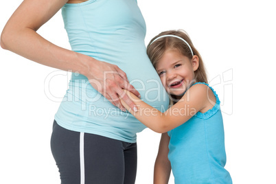 Cute little girl listening to her mothers belly and laughing