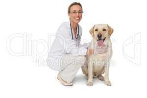 Pretty vet petting yellow labrador dog smiling at camera