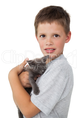 Little boy holding grey kitten smiling at camera