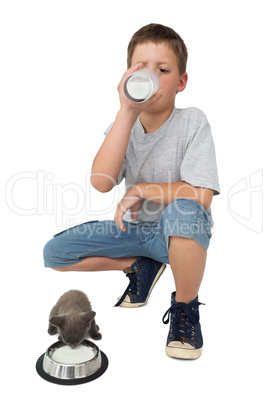 Cute little boy and grey kitten both drinking milk