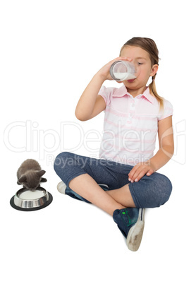 Cute little girl and grey kitten both drinking milk