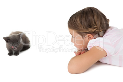 Cute girl looking at grey kitten lying on floor