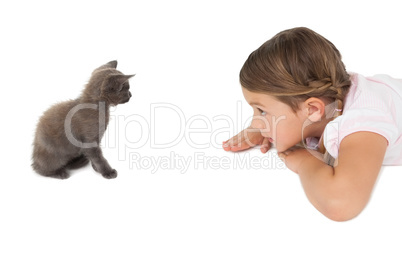 Little girl looking at grey kitten sitting on floor