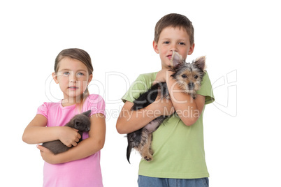 Cute siblings holding their pets and smiling at camera