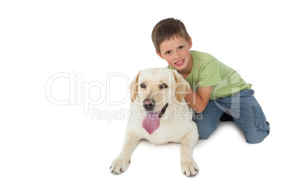 Cute little boy kneeling with his labrador smiling at camera