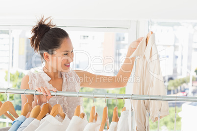Fashion designer looking at shirt beside rack of clothes