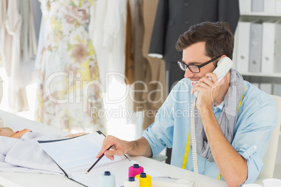 Smiling male fashion designer using phone in the studio