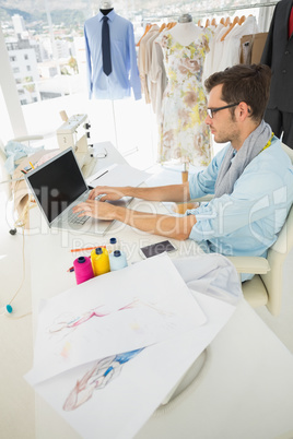 Concentrated young male fashion designer using laptop