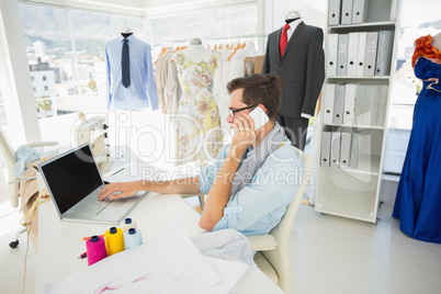 Male fashion designer using laptop and cellphone