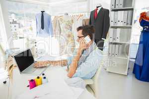Male fashion designer using laptop and cellphone