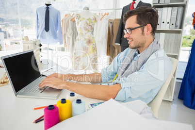 Concentrated young male fashion designer using laptop