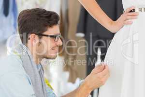 Male fashion designer adjusting dress on model