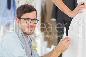 Male fashion designer adjusting dress on model