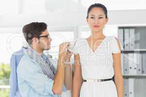 Fashion designer adjusting dress on model