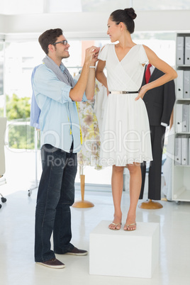 Fashion designer adjusting dress on model