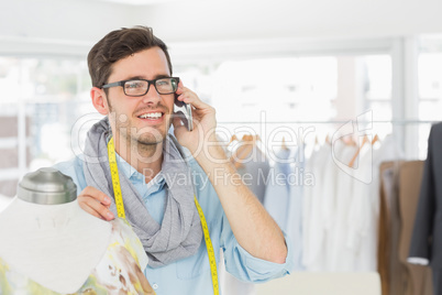 Fashion designer working on dress while using mobile phone