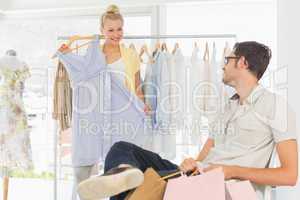 Man with shopping bags while woman selecting a dress