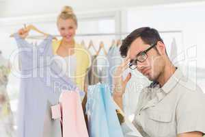 Bored man with shopping bags while woman at clothes rack