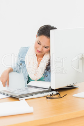 Woman looking at catalog in front of computer