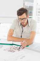 Concentrate male artist sitting at desk with photos