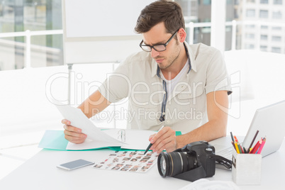Concentrate male artist sitting at desk with photos