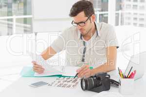 Concentrate male artist sitting at desk with photos