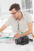 Concentrate male artist sitting at desk with photos