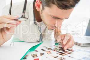 Concentrate male artist sitting at desk with photos