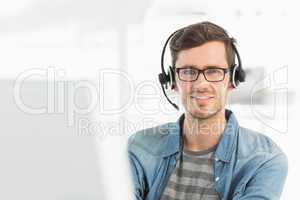 Portrait of a smiling man with headset using computer