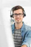 Portrait of a smiling man with headset using computer