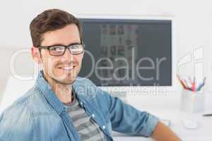 Casual male photo editor in front of computer