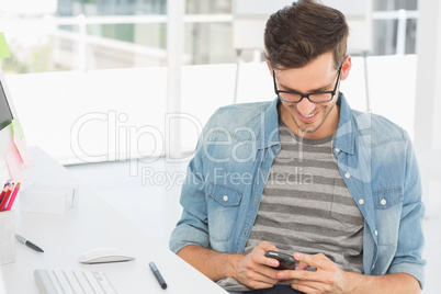 Male artist text messaging in front of computer