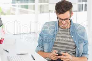 Male artist text messaging in front of computer