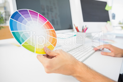 Hand holding color wheel while using computer