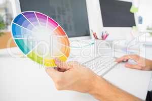 Hand holding color wheel while using computer