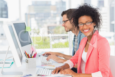 Casual young couple working on computers in office