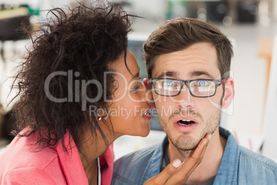 Female artist whispering into colleagues ear