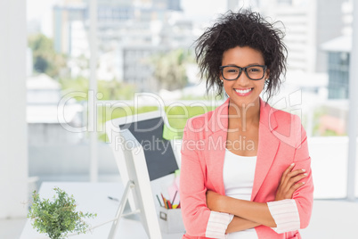Casual female artist with arms crossed at bright office
