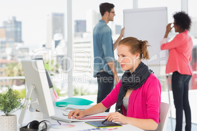 Female artist using graphic tablet with colleagues at office