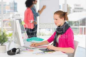 Female artist using graphic tablet with colleagues at office