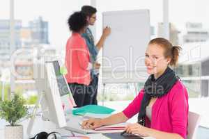 Female artist using graphic tablet with colleagues at office