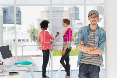 Casual male artist with colleagues in background at office