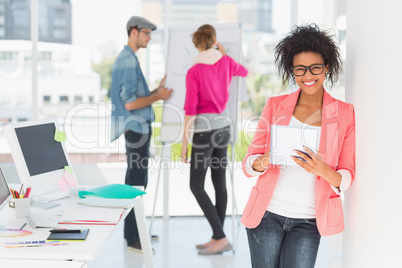 Artist using digital tablet with colleagues in background at off