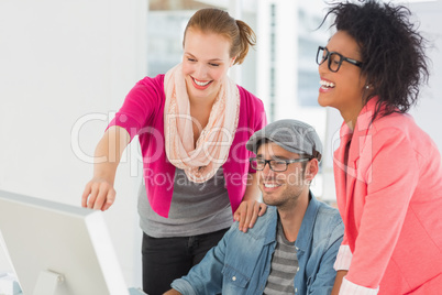 Three cheerful artists working on computer