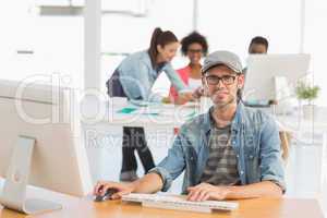 Casual male artist using computer with colleagues in background