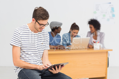 Artist using digital tablet with colleagues in background at off