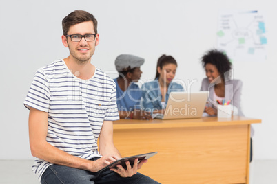 Artist using digital tablet with colleagues in background at off