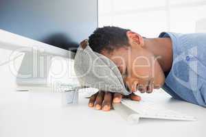Male artist with head resting on keyboard in the office