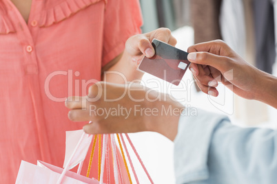 Mid section of customer receiving shopping bags and credit card