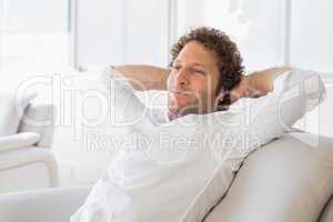 Relaxed man sitting with hands behind head at home